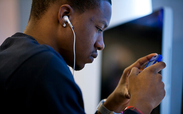 Young African American man looking at smartphone with earphones in his ears