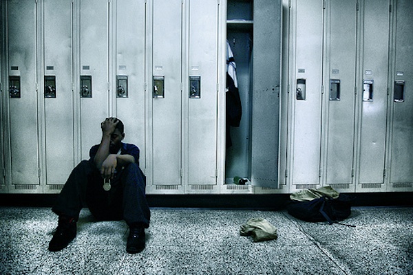 young black male struggling sitting on the ground in front of locker