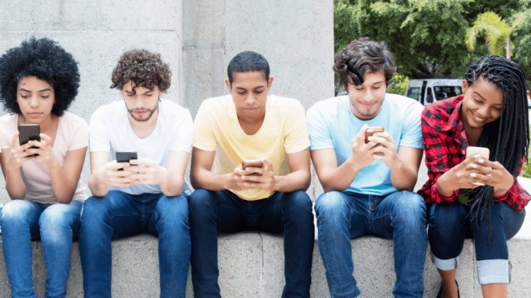 Youth sitting side by side all looking at smartphones