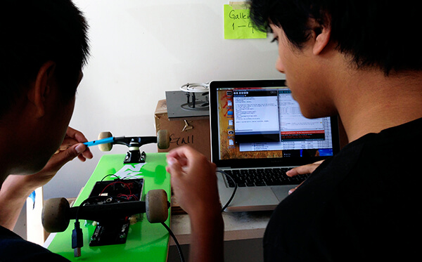 Teens working on Arduino micro controller to create technology enhanced skateboard