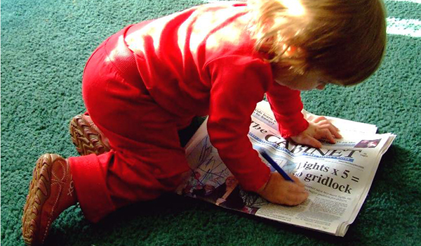 child drawing on newspaper