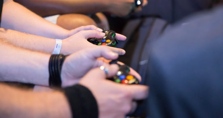 Close up of hands holding game controllers