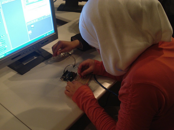 female student working on circuit board at computer desk
