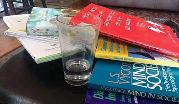 prep for course design with books piled up and empty glass