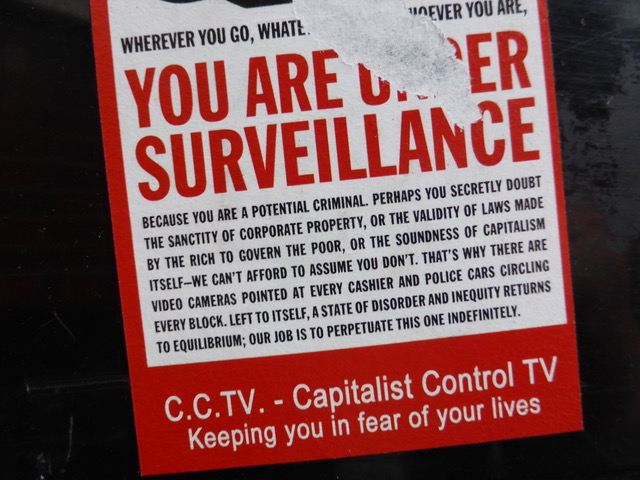 A ripped sign reads in large red capital letters: you are under surveillance