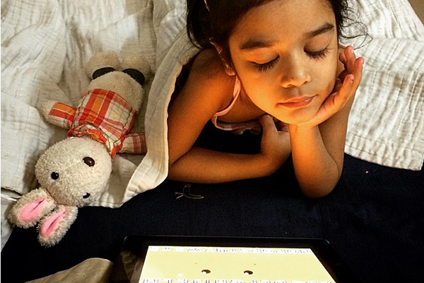 young girl in bed looking at screen