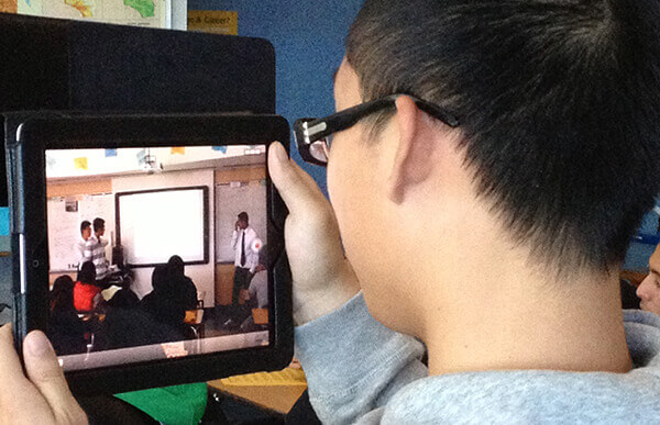boy holding ipad watching classroom video