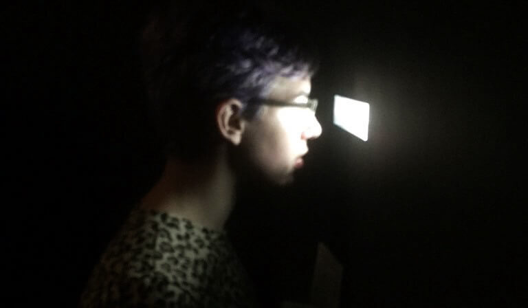 Person looks through small opening in dark room