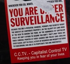 A sign with large capital red letters reads YOU ARE UNDER SURVEILLANCE