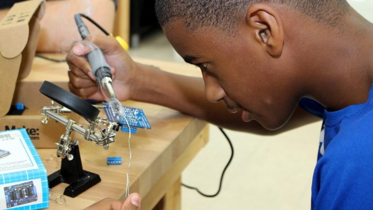 Young teen using soldering iron on electronics
