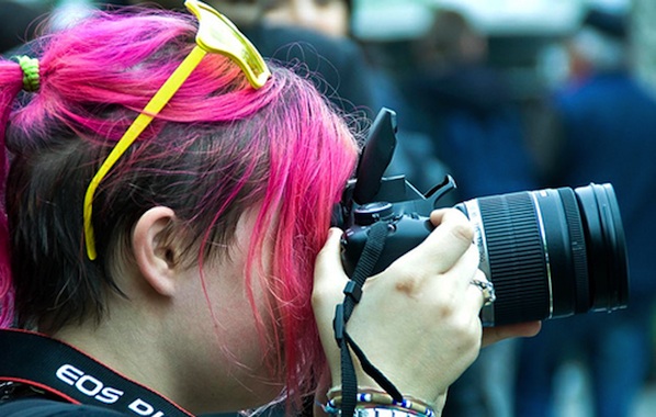 women with pink hair taking a photo on digital camera