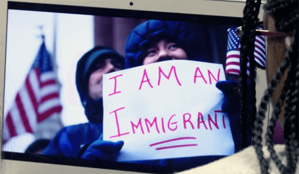 Person holding a sign that says "I am an immigrant"