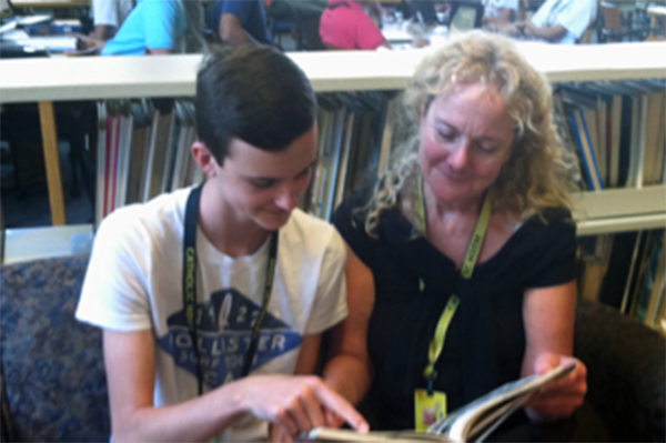 Student and teacher reading book together